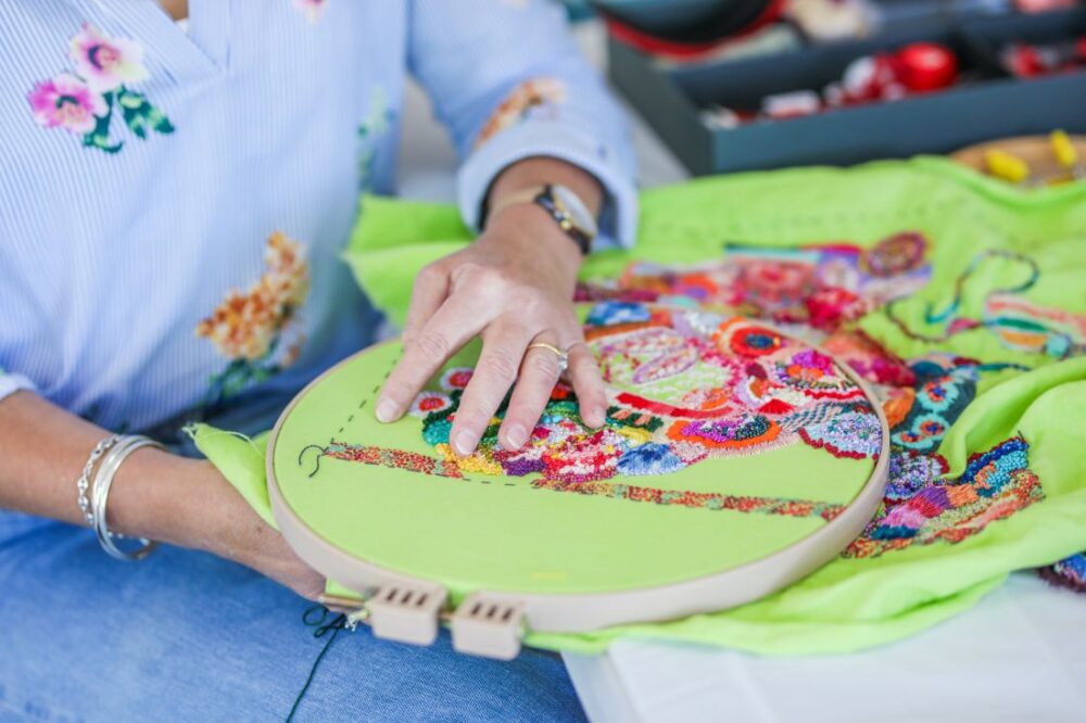 Embroidering vibrant flowers on bright green fabric