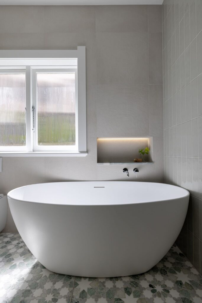 A luxurious freestanding bathtub with ambient lighting, set against neutral tones and natural light streaming through the window
