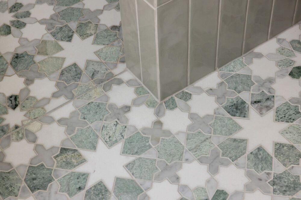 Close-up of a decorative floor tile design featuring green and white star-shaped patterns, with subtle grey accents.