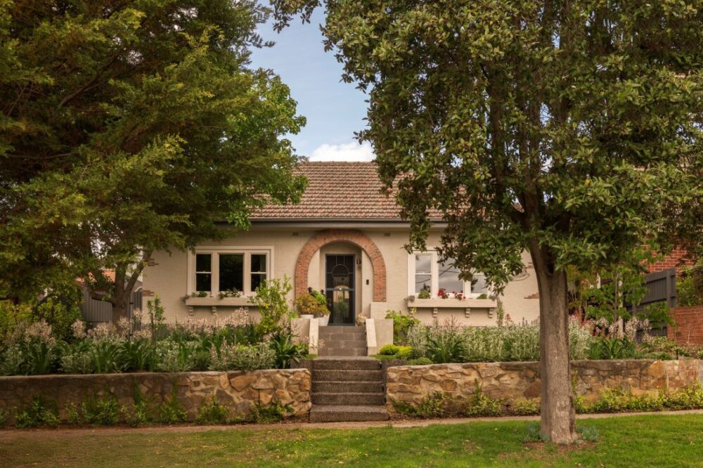 Front view of a classic Camberwell home with stone steps, surrounded by greenery and mature trees.