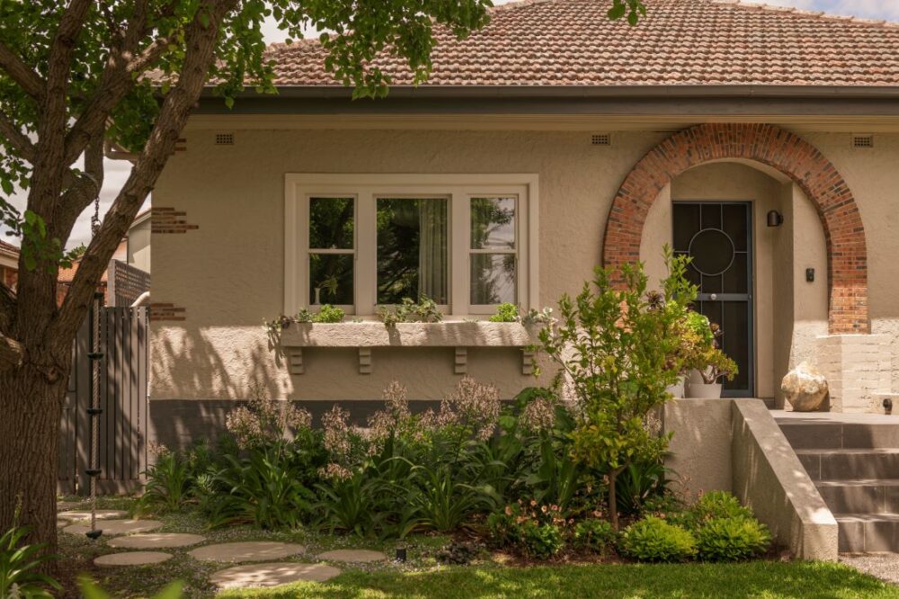 Front view of a Camberwell home featuring a lush garden, stone steps, and a beautiful arched entrance.