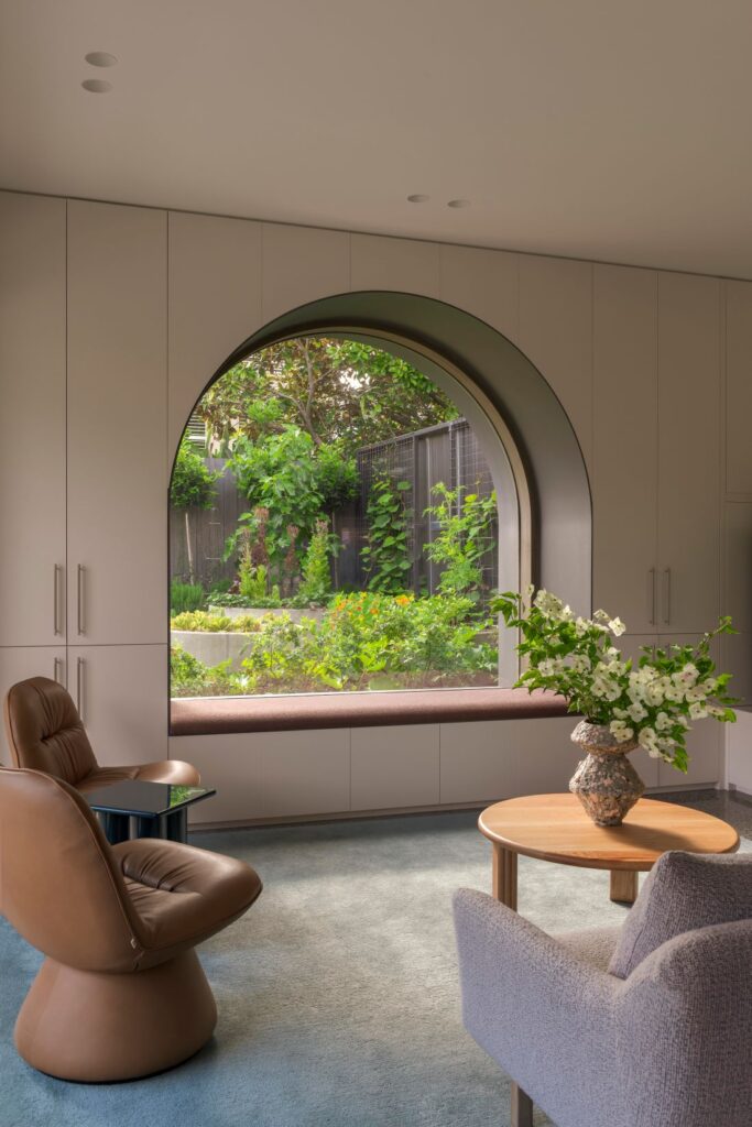 Cozy living room with a stylish circular window offering a view of the lush garden outside.