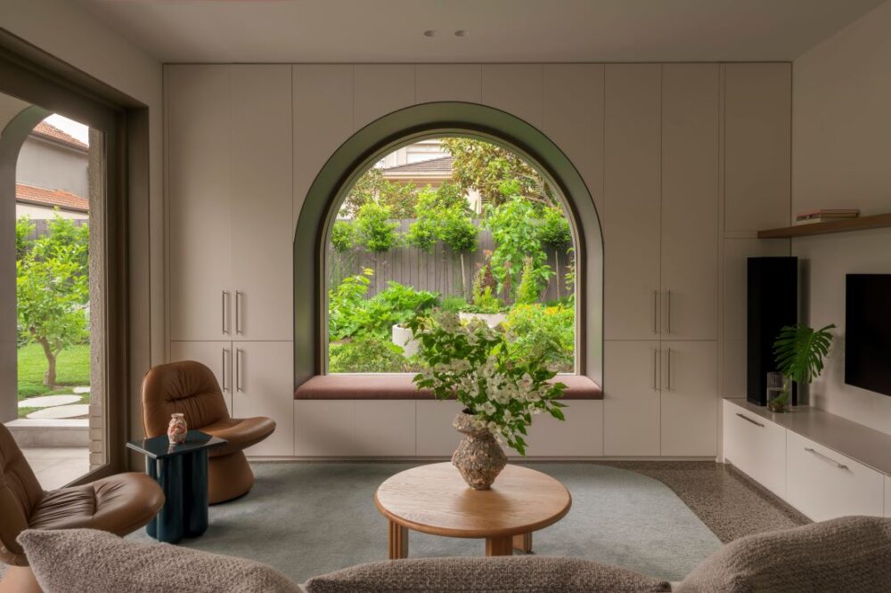 Contemporary living room with a curved window, showcasing a vibrant garden outside.