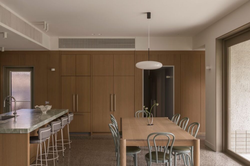 Open-plan kitchen and dining area with natural wood cabinetry and stylish dining chairs.