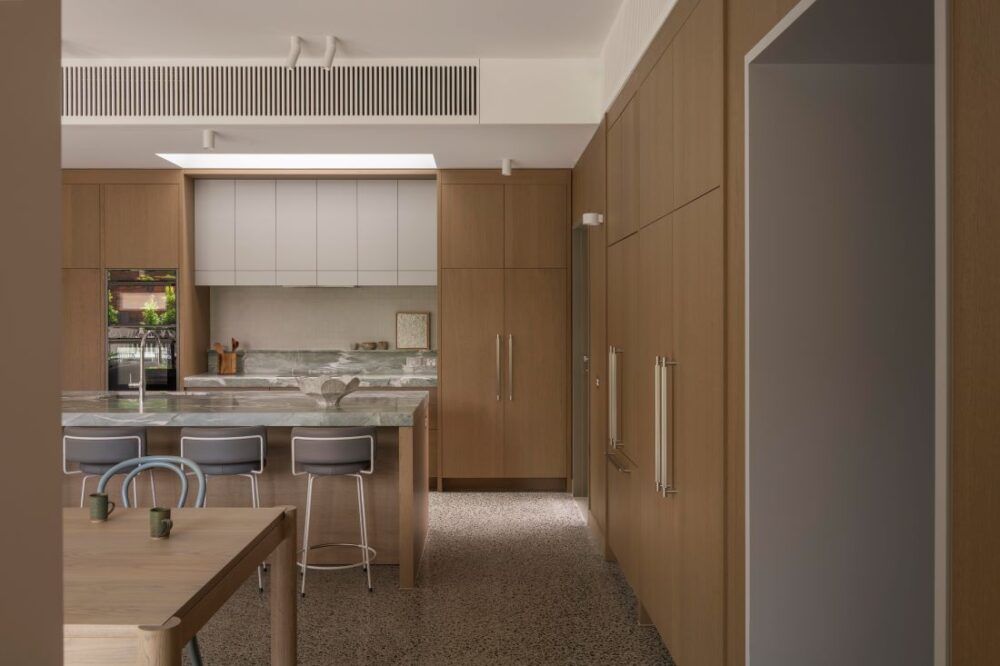 Contemporary kitchen with natural wood cabinetry, marble countertop, and minimalist design.