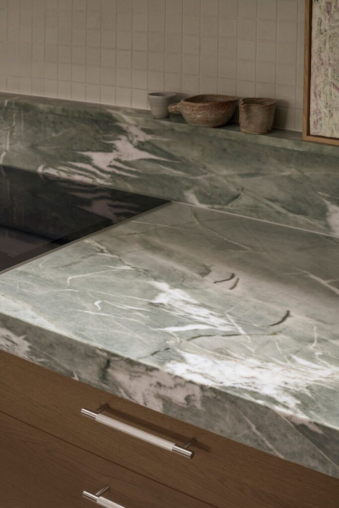 Detailed view of a marble countertop with natural green veining and minimalistic decor.