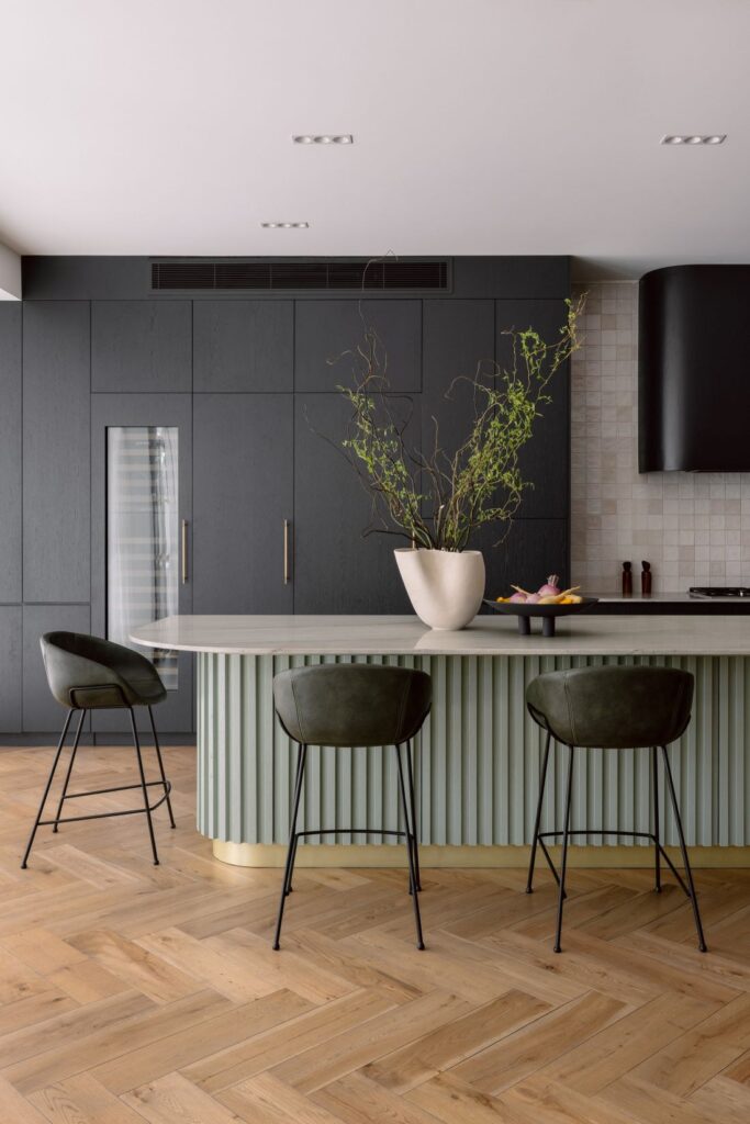 Contemporary kitchen with a sculptural island, dark cabinetry, and stylish bar stools.