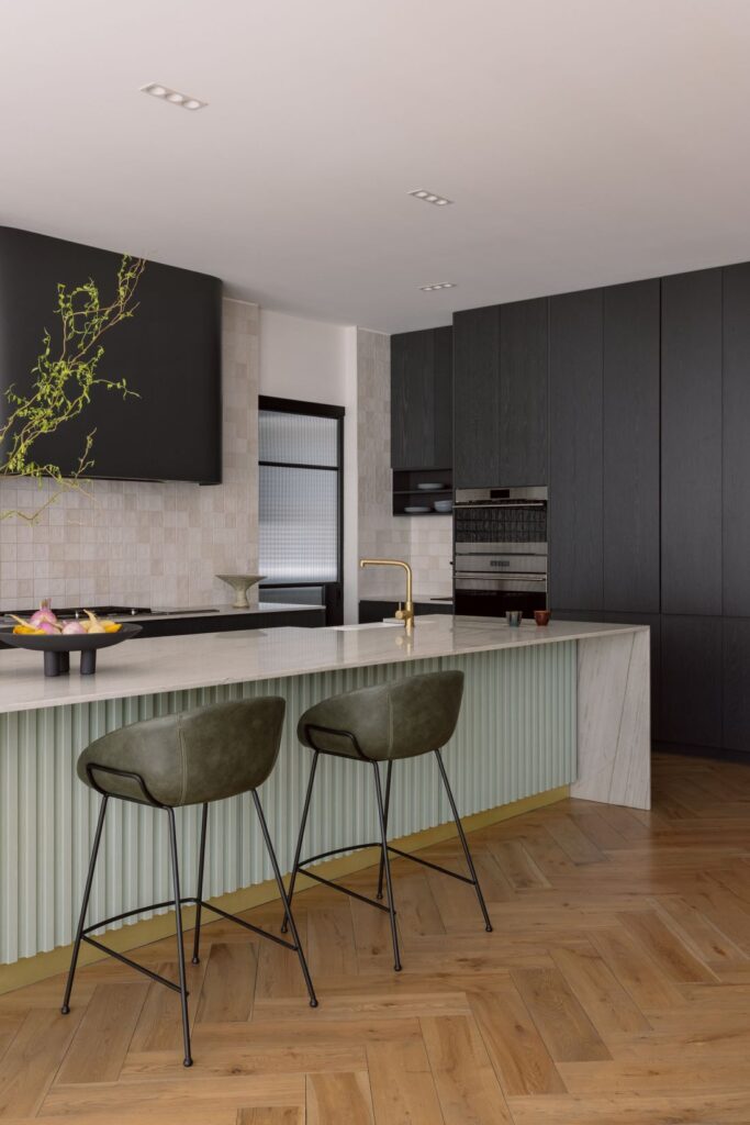 Contemporary kitchen with a sculptural island, dark cabinetry, and sleek marble finishes.