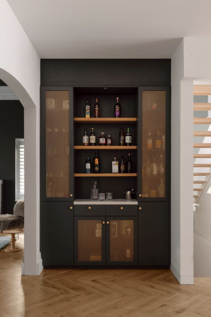 Custom bar unit with brass accents, shelving for bottles, and sleek cabinetry.