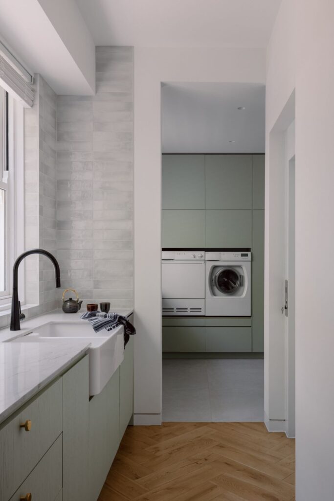 Modern laundry with soft green cabinetry, a deep sink, and built-in appliances.