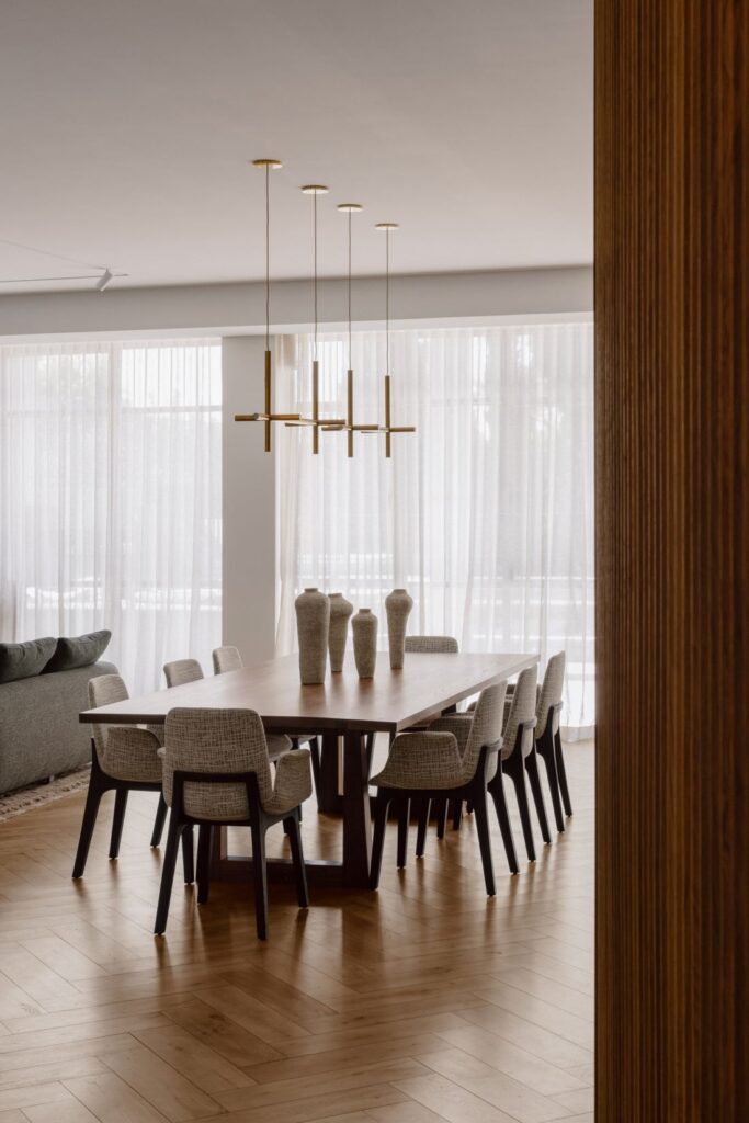 Dining room with a large wooden table, modern pendant lighting, and sculptural vases.