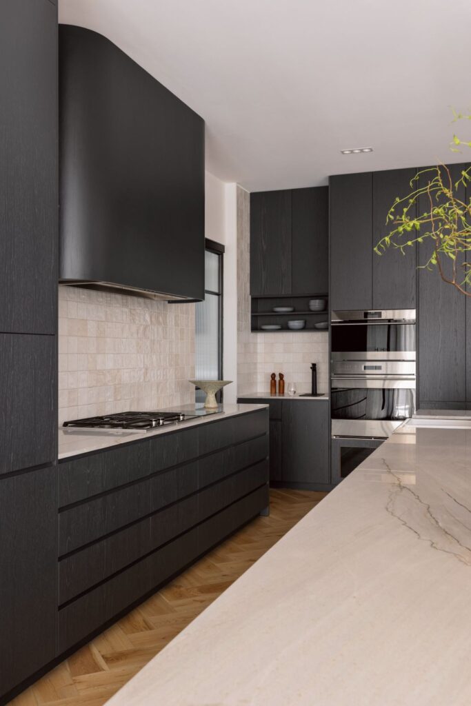 Modern kitchen featuring dark cabinetry, marble countertops, and high-end appliances.