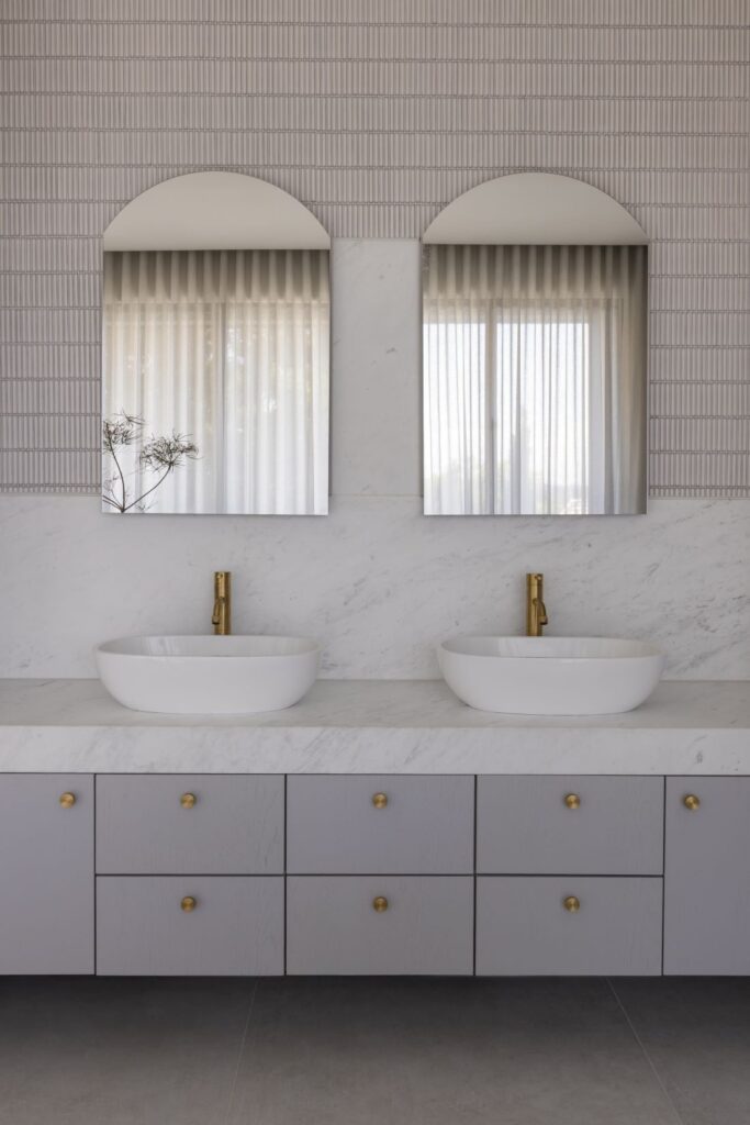 Contemporary bathroom with a double vanity, marble countertop, and brass fixtures.