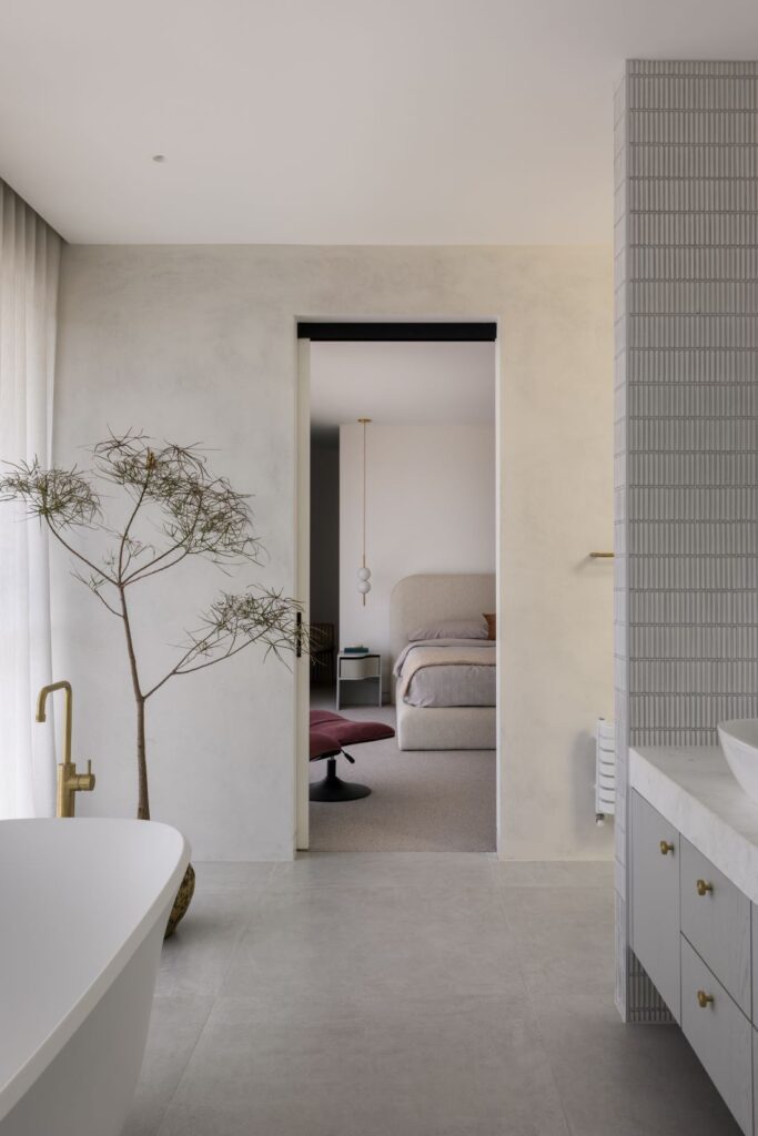 Elegant bathroom with freestanding tub, brass faucet, and a view into the serene bedroom.