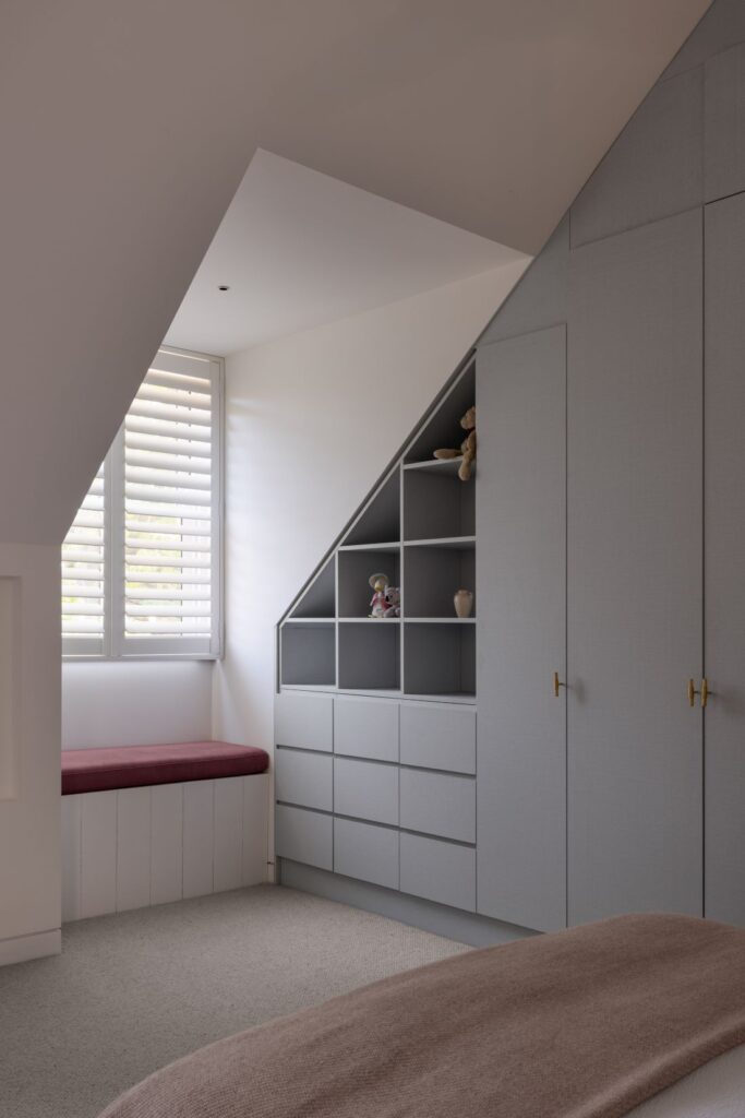 Bedroom corner with custom shelving, built-in storage, and a cozy window bench.