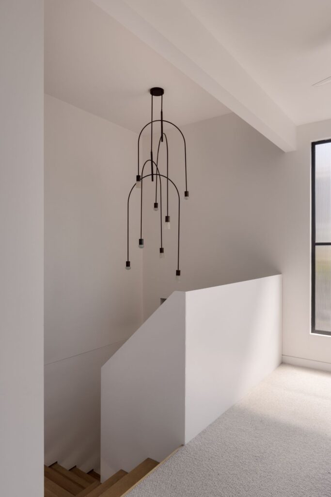 Minimalist staircase with natural wood steps and a sculptural pendant light overhead.