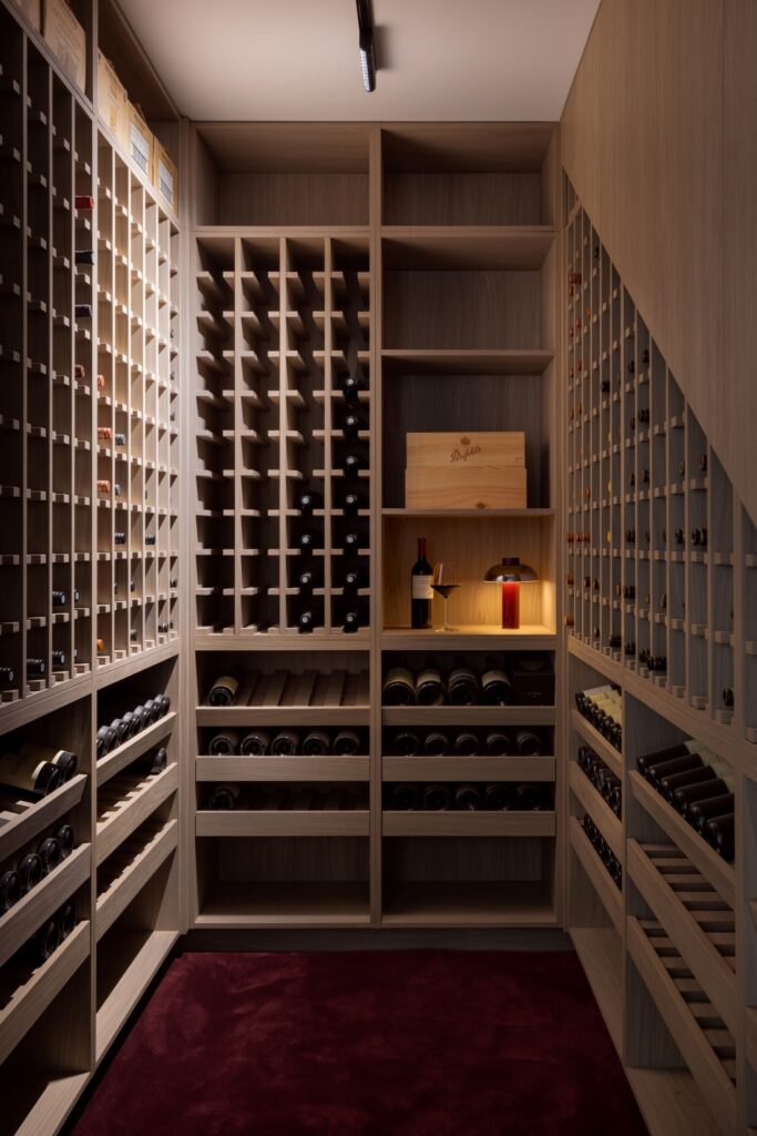 Wine cellar with wooden shelving, neatly organized bottles, and ambient lighting.