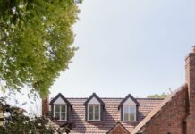 Charming Tudor-style home with a brick facade, welcoming pathway, and vibrant garden.