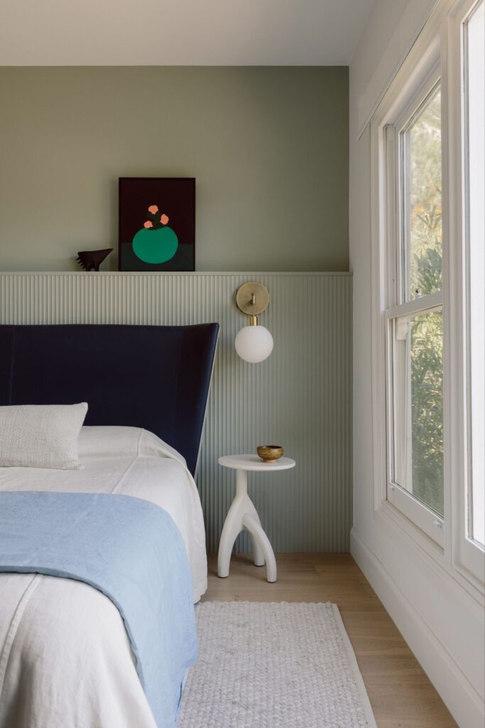 Bedroom with blue throw and green fluted half-height wall