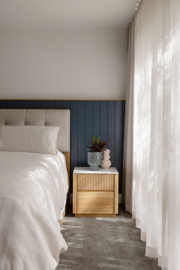 Bedroom with neutral bedding and green half height feature wall from YDM Design Studio