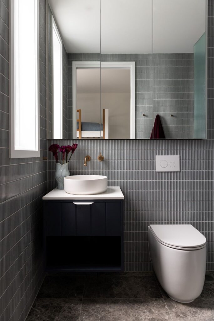 Stylish bathroom with modern sink, gold fixtures, and geometric tile by Annie Bowen at North Avoca Beach House.