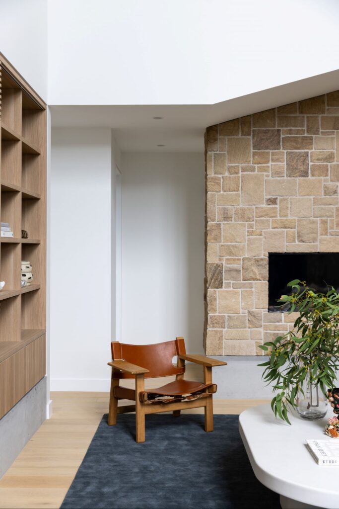 Inviting seating corner with leather chair and stone wall feature by Annie Bowen at North Avoca Beach House.