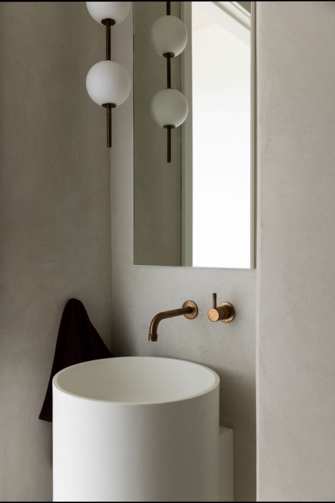 Contemporary bathroom with round sink, brass fixtures, and modern lighting by Annie Bowen at North Avoca Beach House.