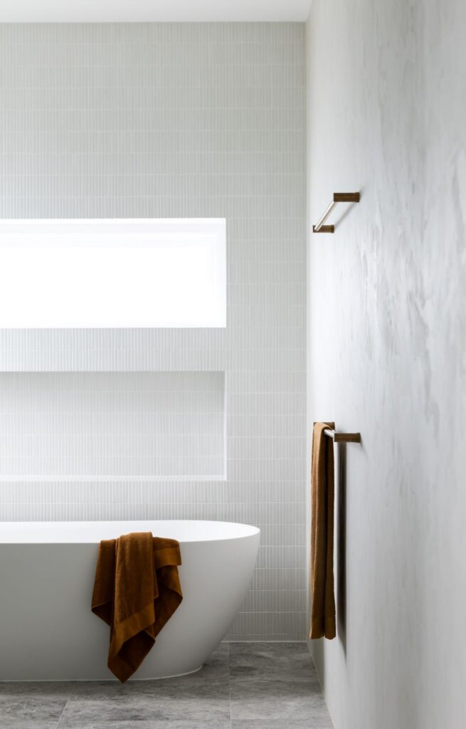 Elegant bathroom with freestanding tub, gray tiles, and modern fixtures by Annie Bowen at North Avoca Beach House.