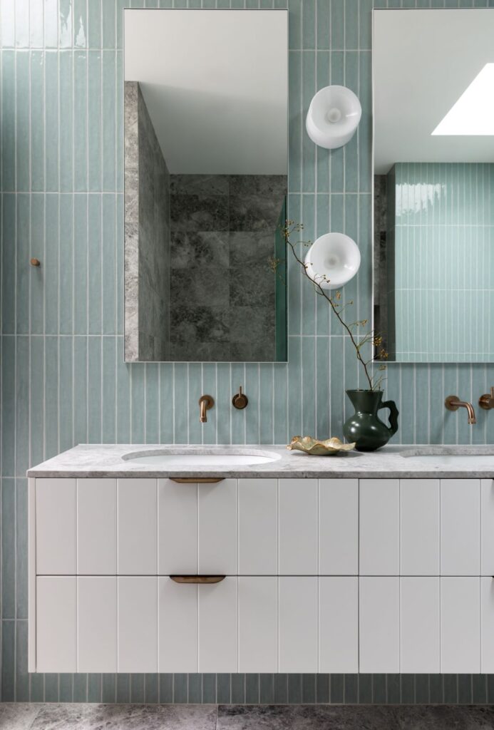 Stylish bathroom with blue vertical tiles, modern vanity, and brass fixtures by Annie Bowen at North Avoca Beach House.