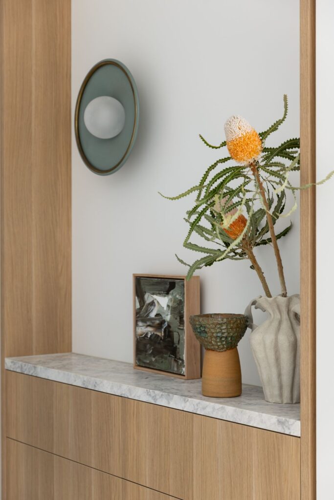 Stylish shelf with art, decorative vase, and modern lighting by Annie Bowen at North Avoca Beach House.