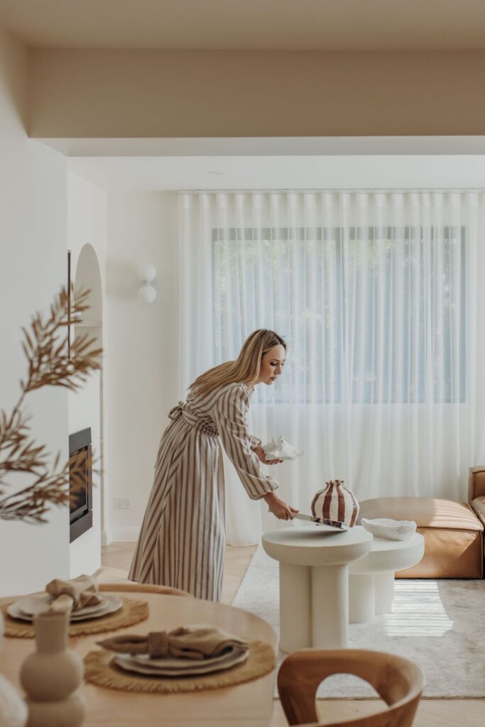 Sabina styling modern living room with round coffee tables, leather sofa, sheer curtains, and neutral décor.