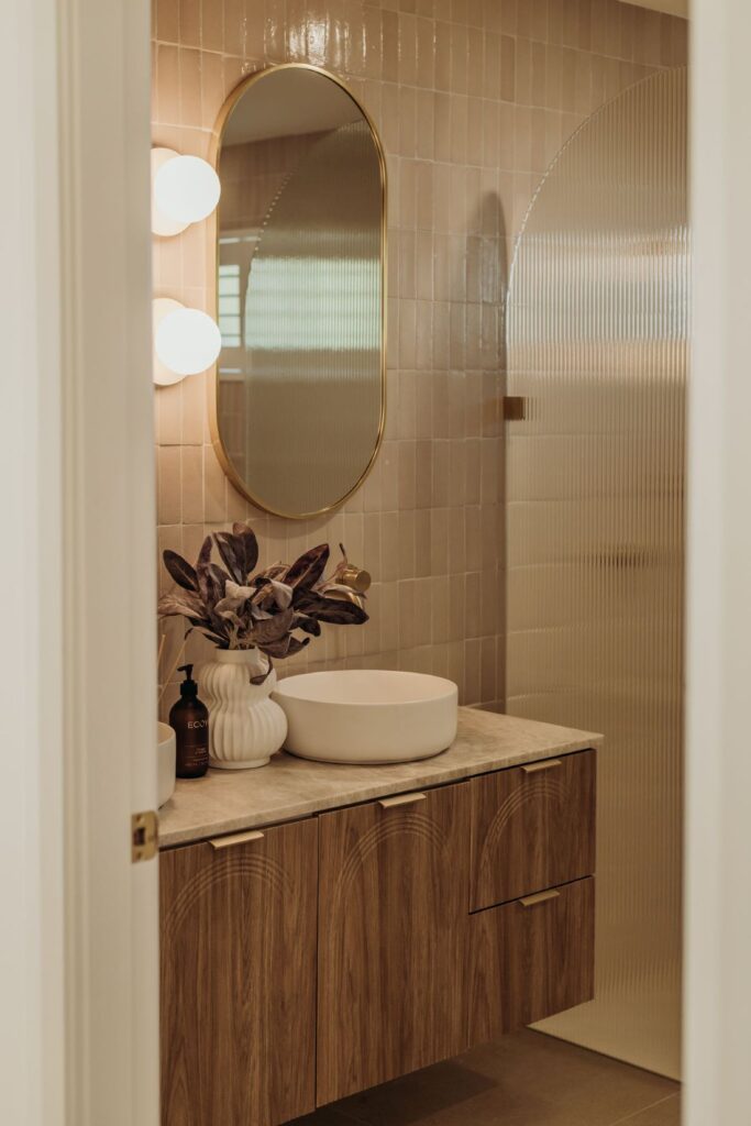 Elegant bathroom vanity with round mirror and modern lighting by Sabina Christine Interiors at 48 Bilwara Avenue.