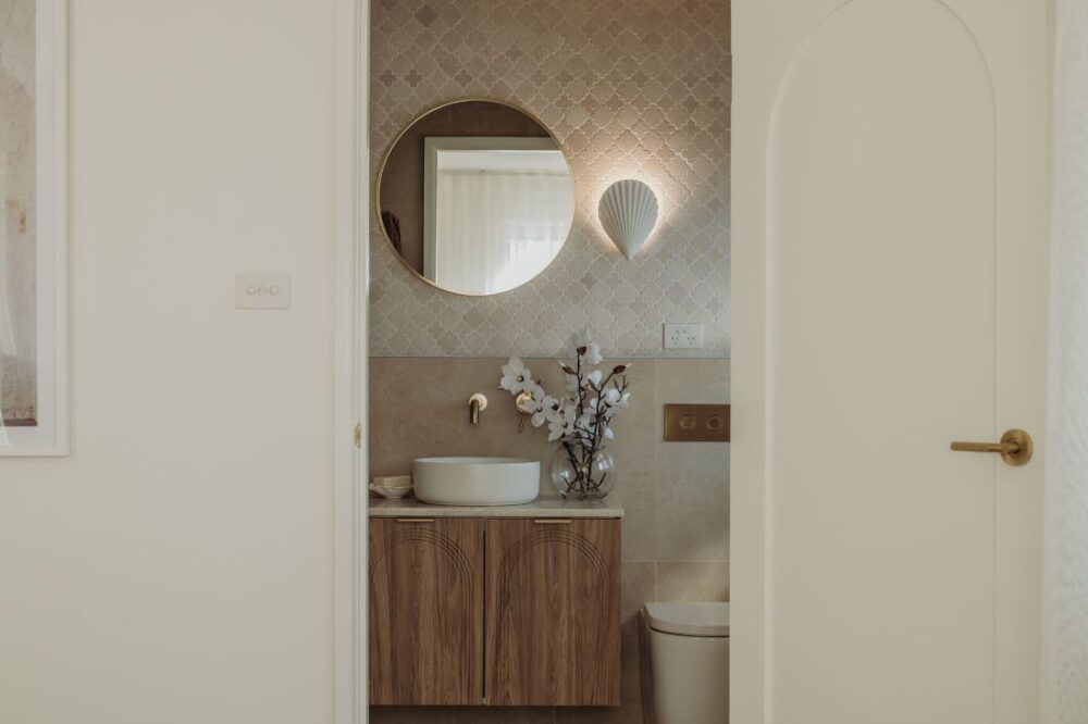 Refined bathroom design with round mirror, wooden vanity, and modern lighting by Sabina Christine Interiors at 48 Bilwara Avenue.