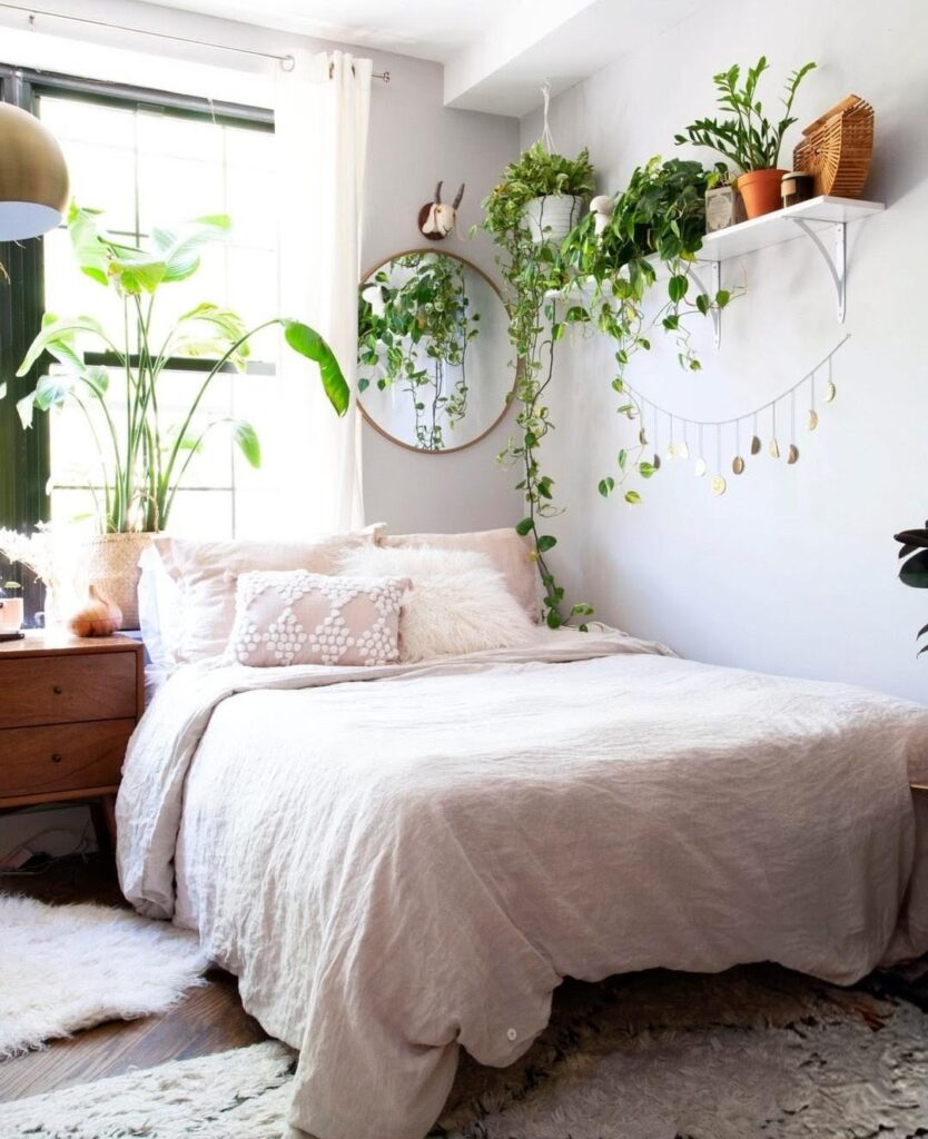 White bedroom with round mirror and trailing plants