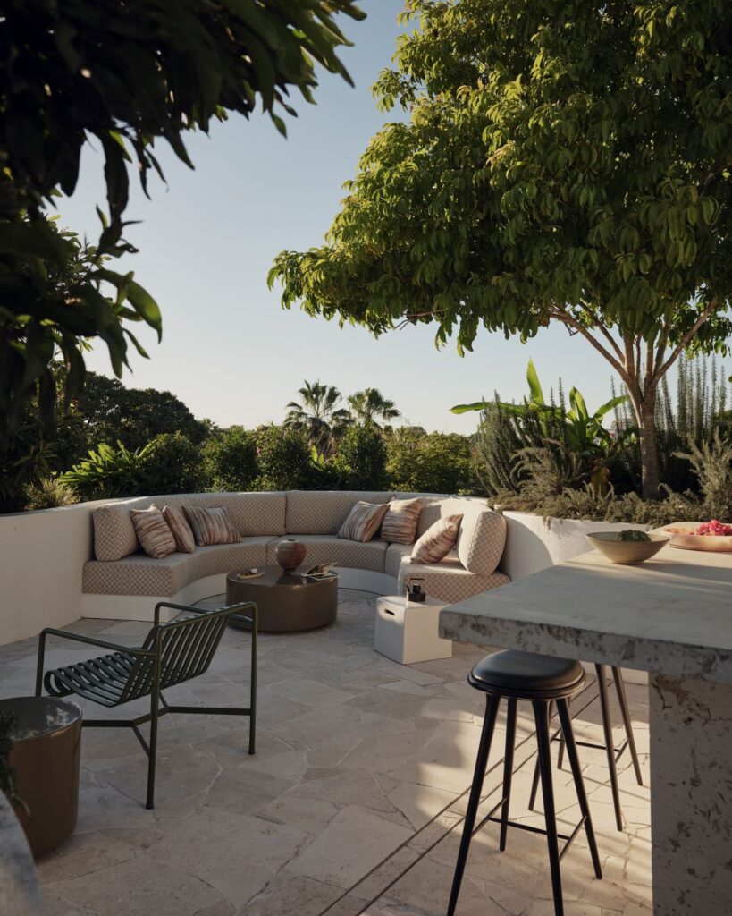 Curved outdoor seating with cushions under large tree
