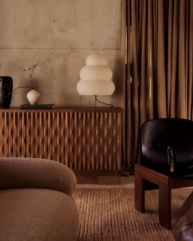Textured wooden cabinet with sculptural lamp and ceramics