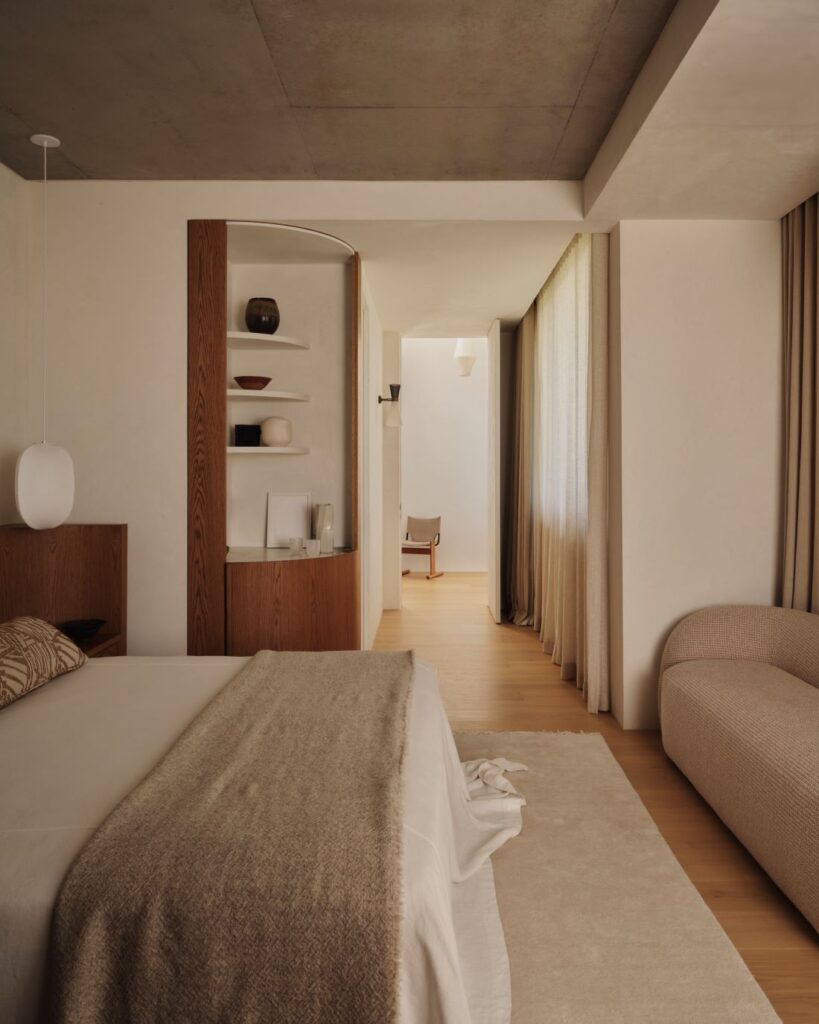 Bedroom with beige linens, textured sofa, and wooden accents