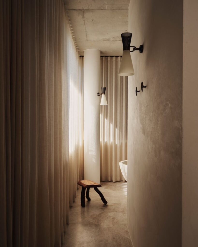 Sunlit corridor with floor-to-ceiling curtains and wall sconces