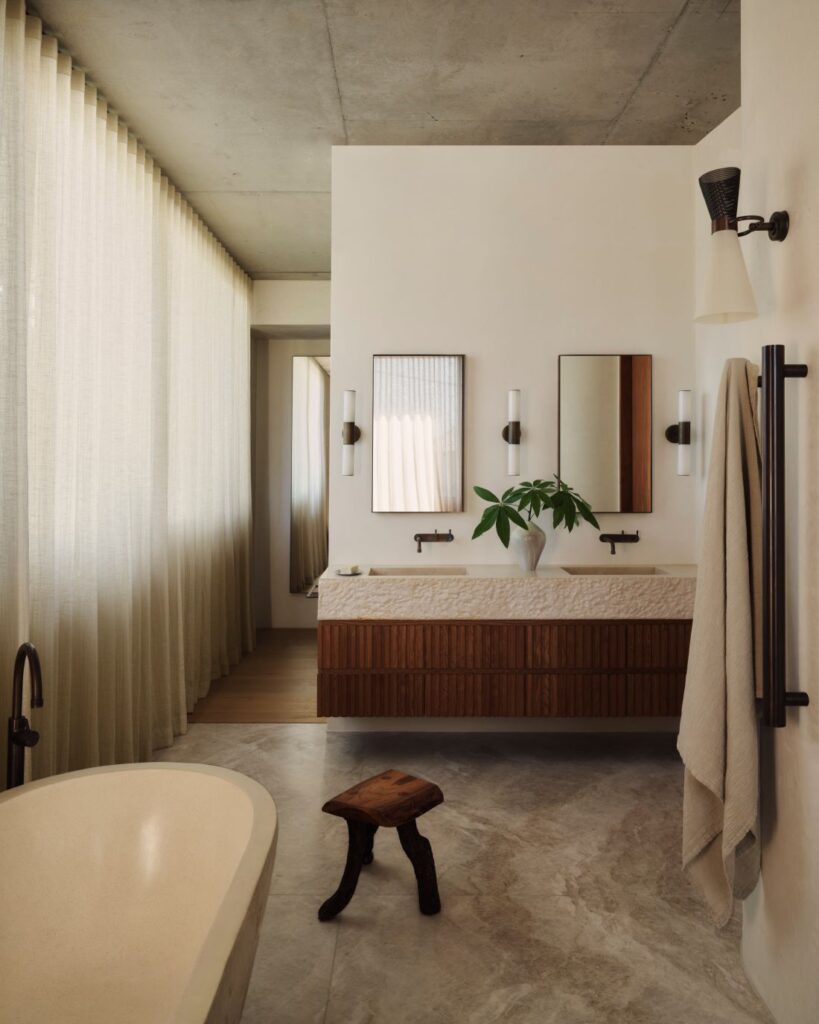 Bathroom with freestanding tub, double vanity, and sheer curtains