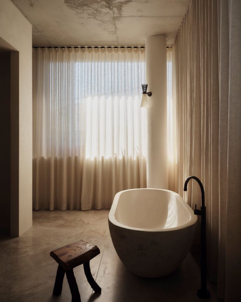 Modern freestanding bathtub near sheer curtains and stool