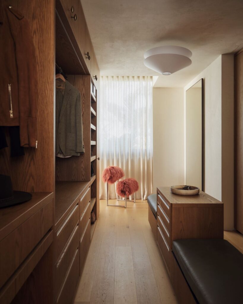 Luxury walk-in wardrobe with wooden cabinetry and pink stools