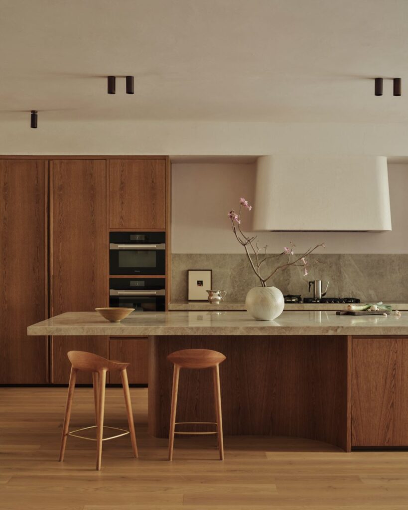Kitchen with marble island, wooden cabinetry, and stools