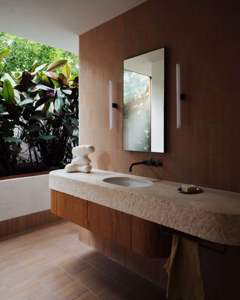 Bathroom with textured vanity, mirror, and greenery outside