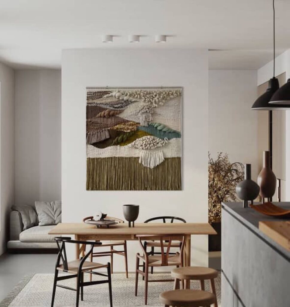 Handwoven textile artwork in neutral and earthy tones above dining table