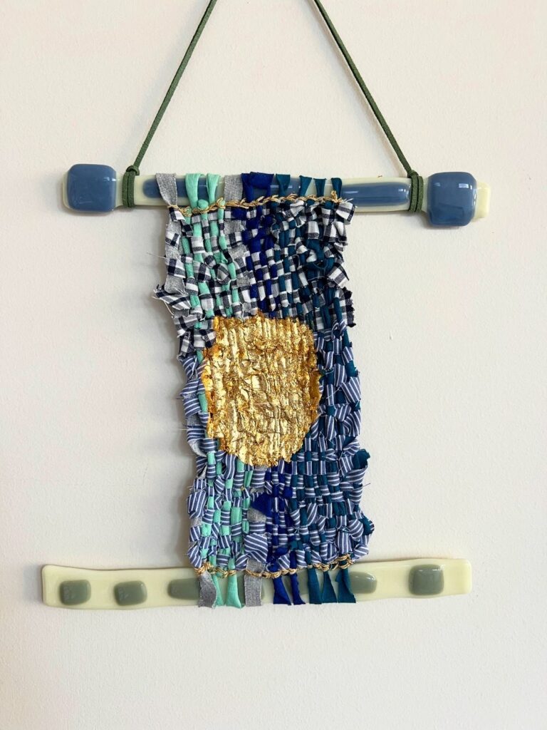 Handwoven textile artwork with blue tones and gold centre