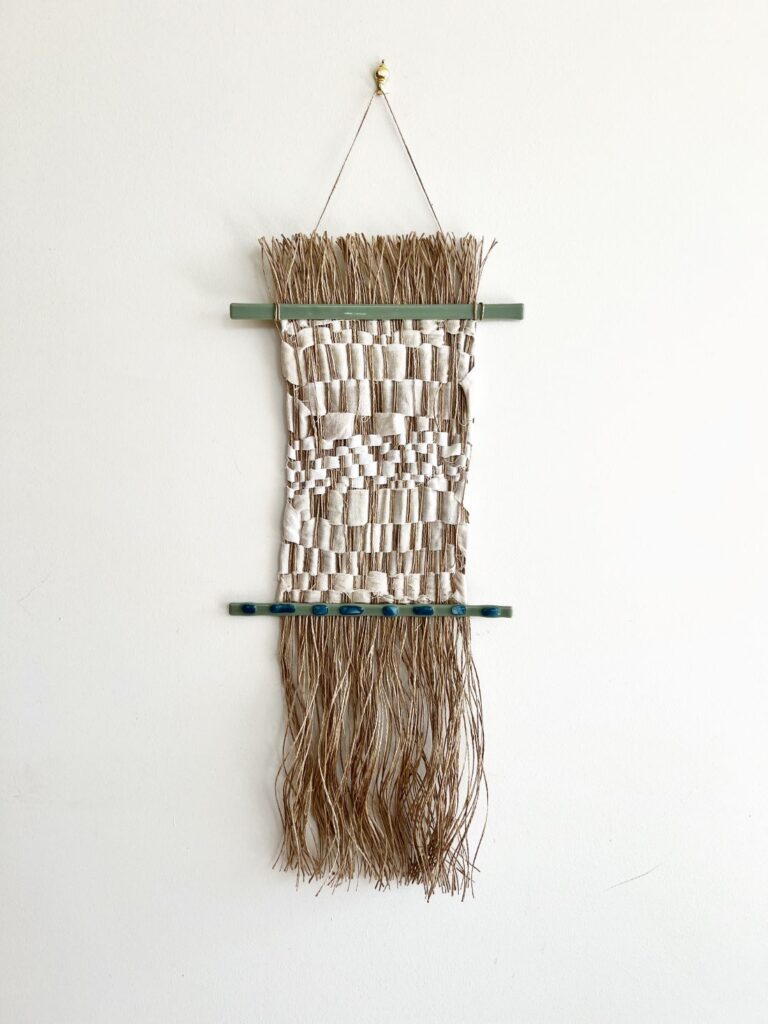 Vertical woven textile wall hanging with natural fibres and wooden rods