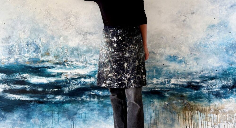 Abstract painting with blue and beige textured layers, studio apron visible
