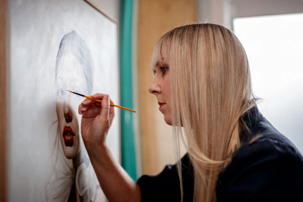 Artist painting hyper-realistic female portrait on canvasd