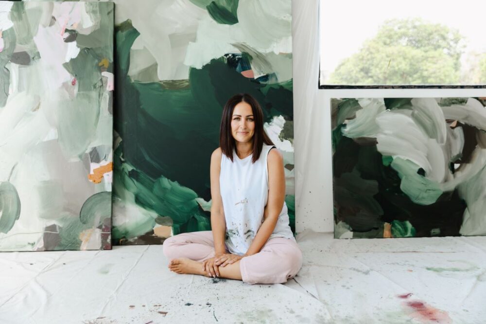 Alisha Falconer seated with green abstract paintings