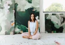 Alisha Falconer seated with green abstract paintings